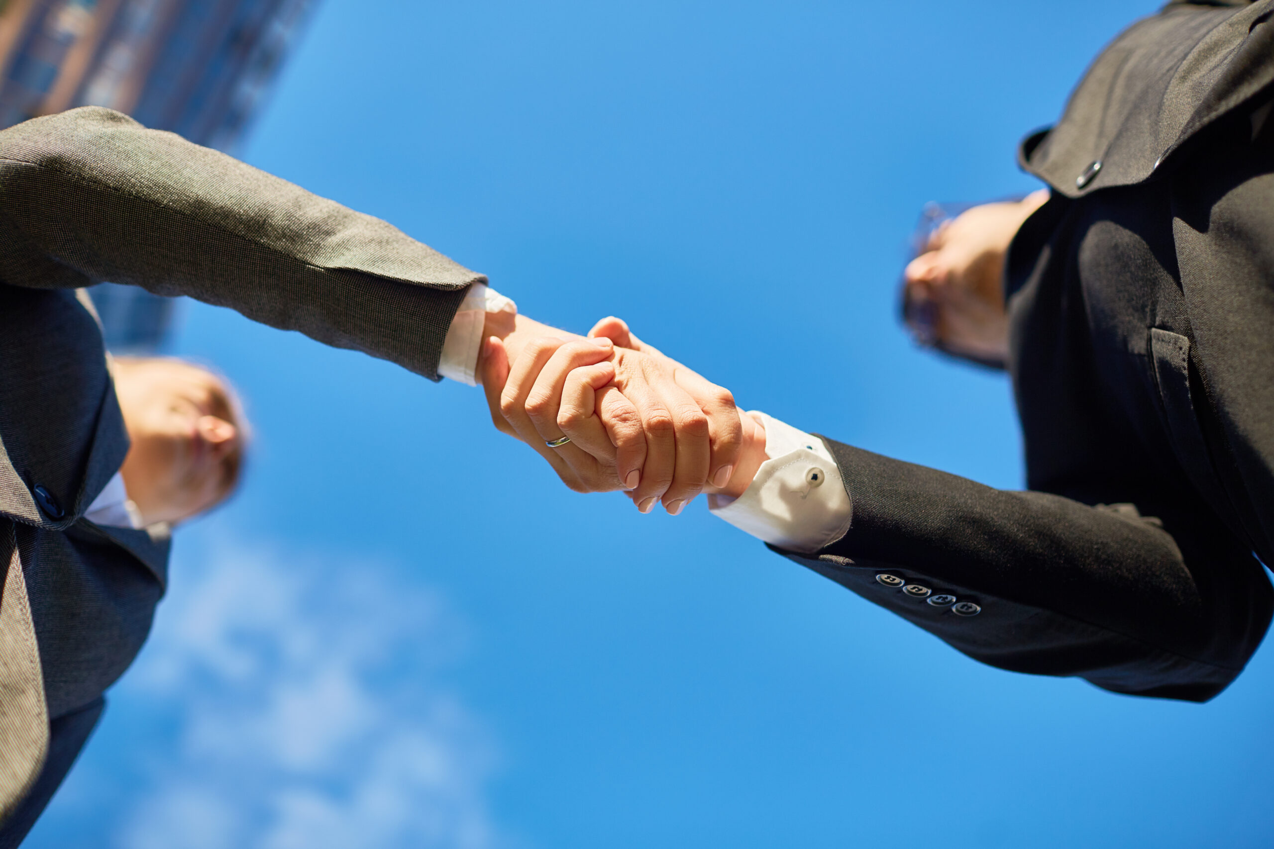 Low angle shot capturing professional handshake between two professionals, showing business partnership.