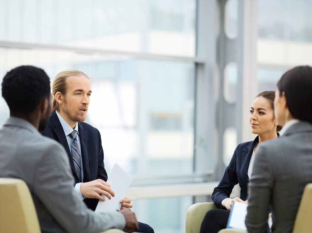 Business professionals exchange ideas in a meeting, highlighting conversation starters in building relationships.